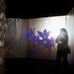 A visitor views an immersive projection of flowers in ultraviolet colours, illustrating how bees perceive their environment.