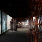 Visitors viewing animated wildflower meadow projections that transition from dawn to dusk in an immersive exhibition space.